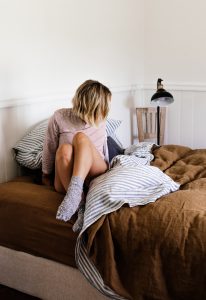Lady getting into bed wearing socks